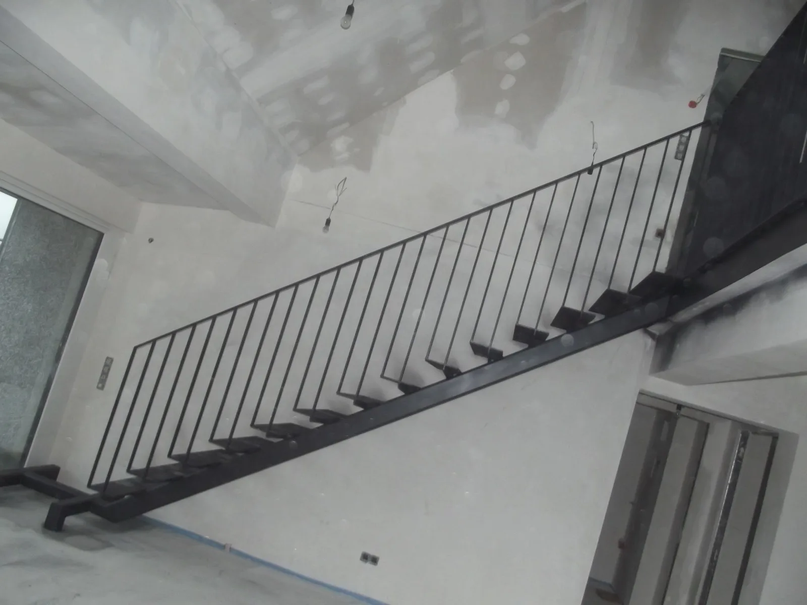 Stahltreppe mit schwarzem Stabgeländer in einem Rohbau